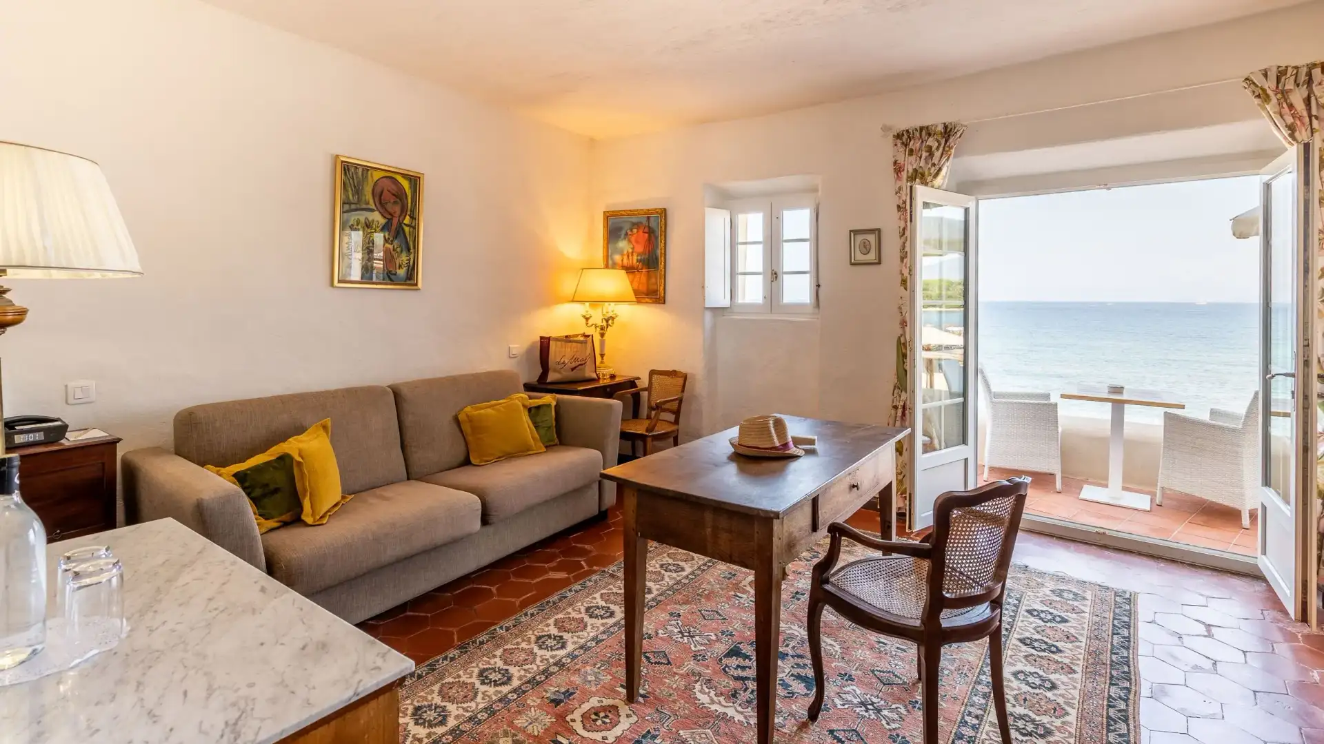 Salon avec canapé, table et chaises, donnant sur une terrasse avec vue sur la mer