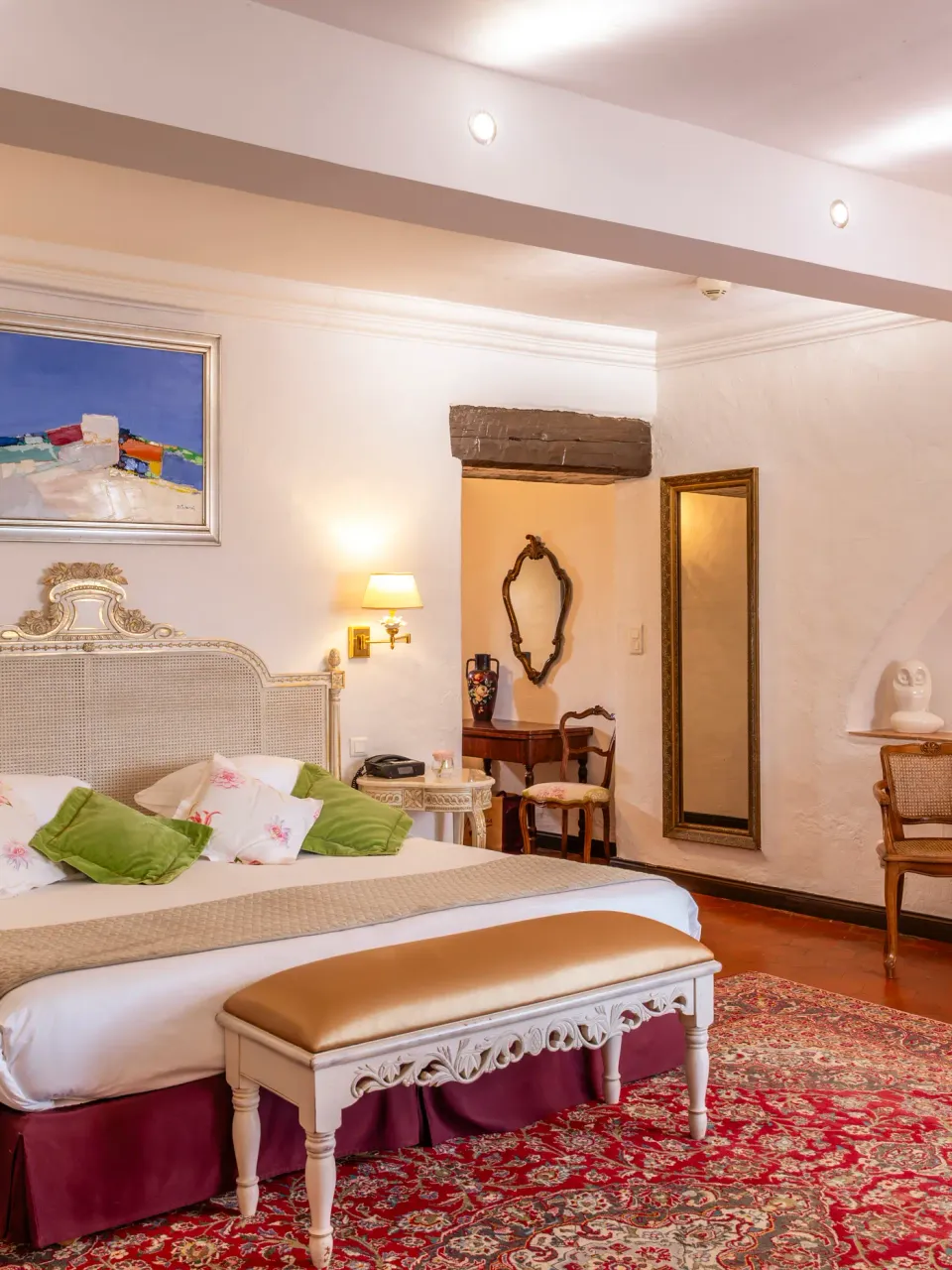 Chambre avec un lit à baldaquin, des tables de chevet, un bureau, des lampes murales et des œuvres d'art accrochées aux murs
